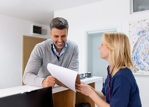 Patient and dental team member speaking at front desk