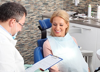 Dentist holding clipboard while talking to patient