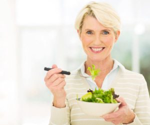 Senior woman smiling and eating a salad