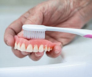 Brushing full denture over the sink