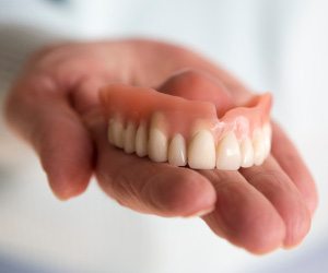 Close up of hand holding a full denture