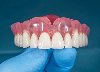 Dentist in Fresno holding dentures