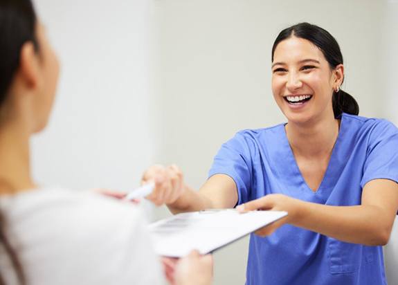 a front desk team member giving out patient forms