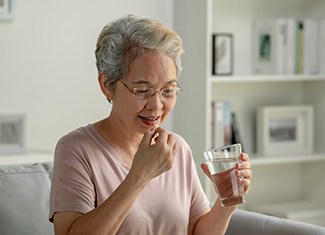 a woman taking a pill with a glass of water