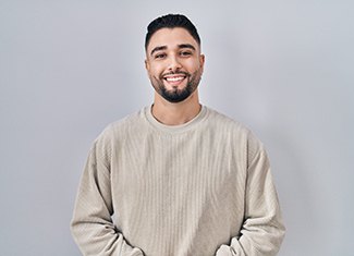 a smiling man in a tan, long-sleeved shirt