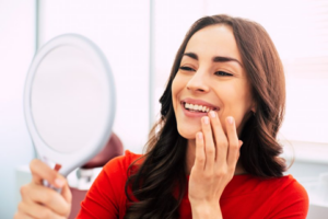 Woman examining her beautiful smile in a small mirror